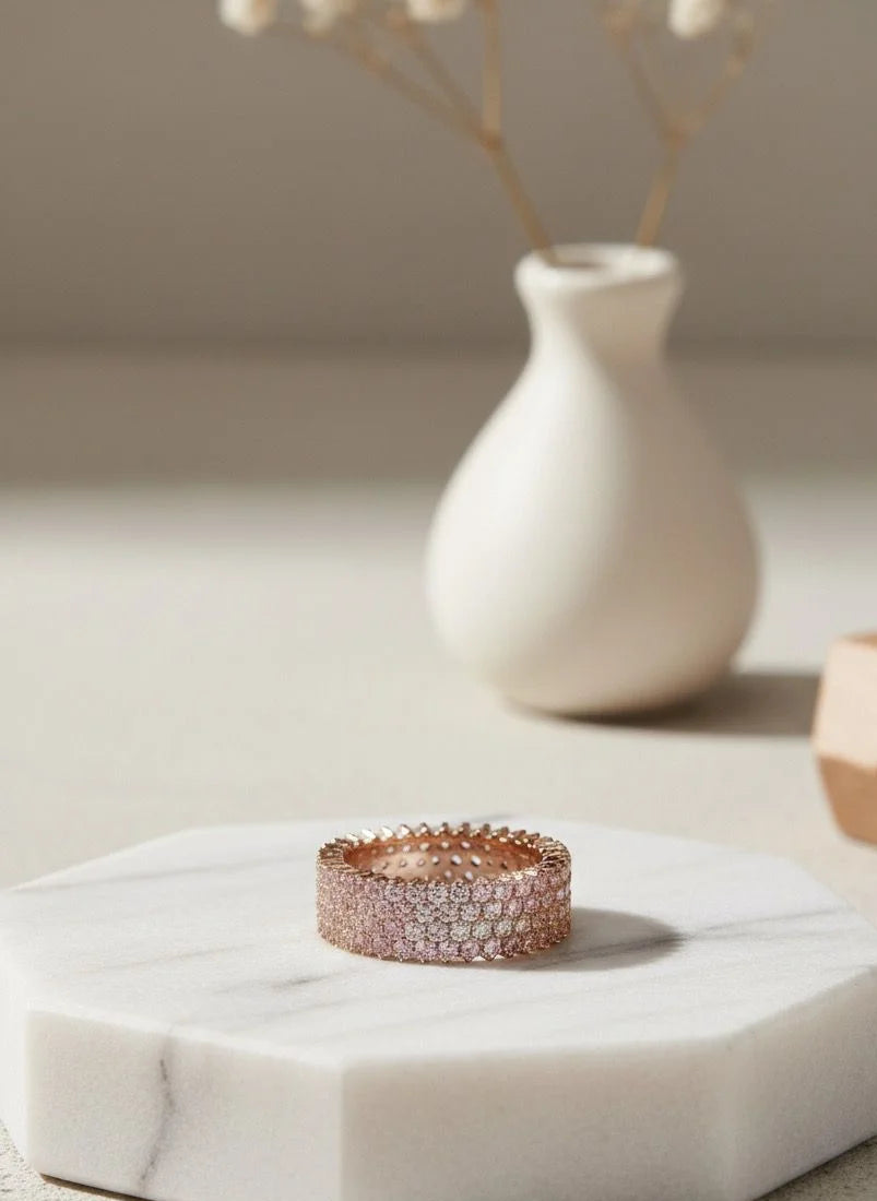 Rose gold ring on a hexagonal marble coaster with a vase in the background