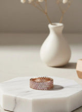 Rose gold ring on a hexagonal marble coaster with a vase in the background