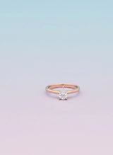 Rose gold ring with a diamond on a light purple background