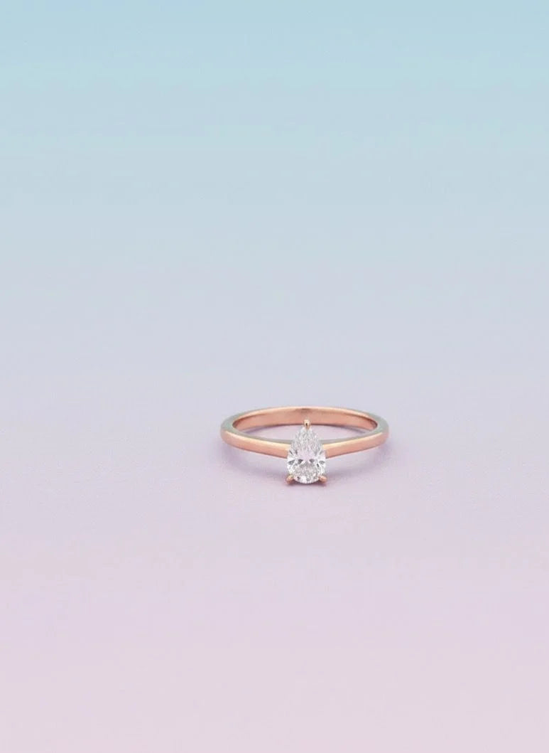 Rose gold ring with a diamond on a light purple background