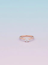 Rose gold ring with a diamond on a light purple background