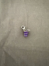 Purple and silver striped cool drink charm on a gray fabric background