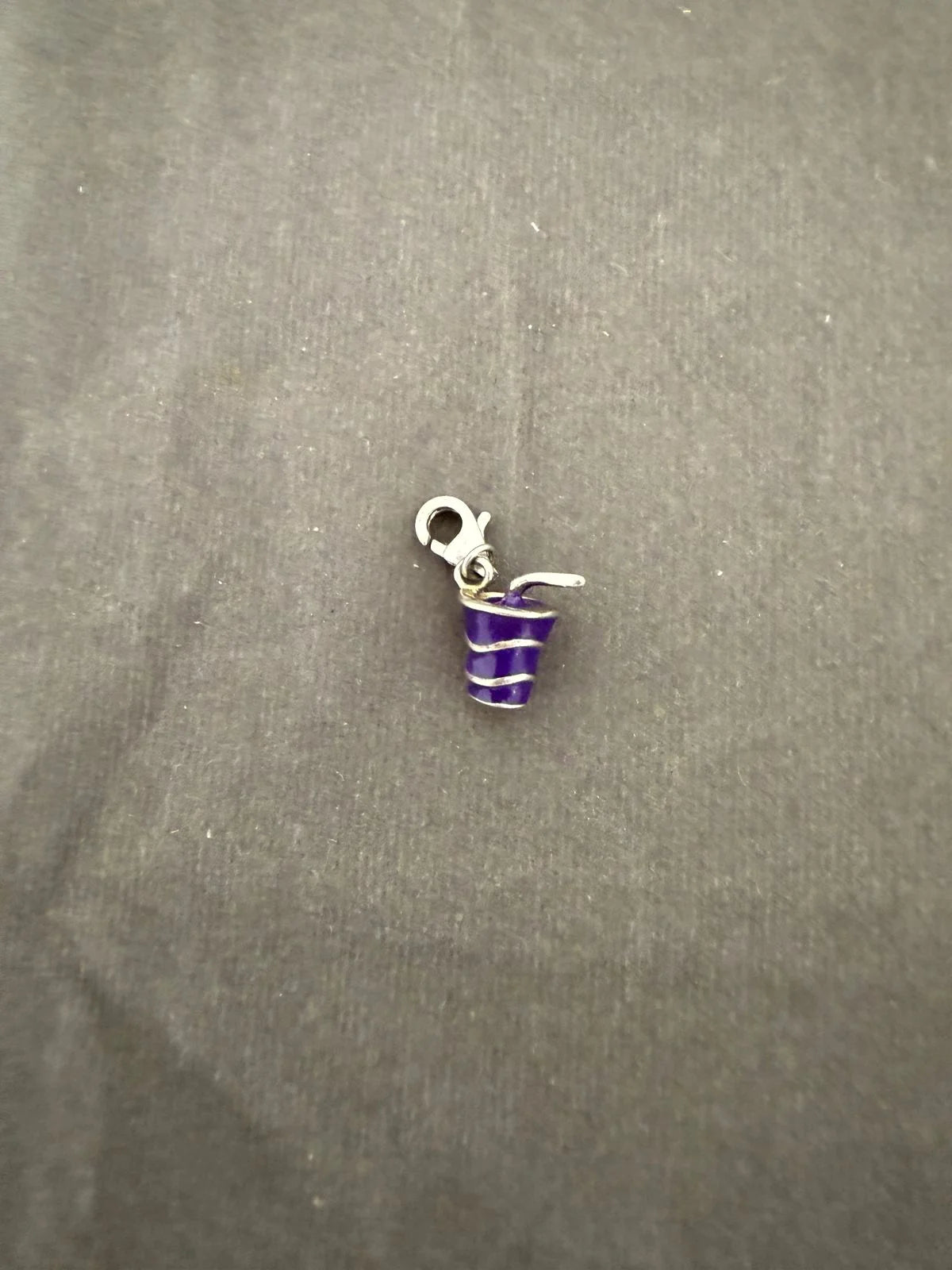 Purple and silver striped cool drink charm on a gray fabric background