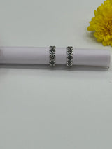 Two silver toe rings with floral designs on a white surface with a yellow flower in the background.