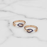 Two gold toe rings with blue gemstones on a marble surface