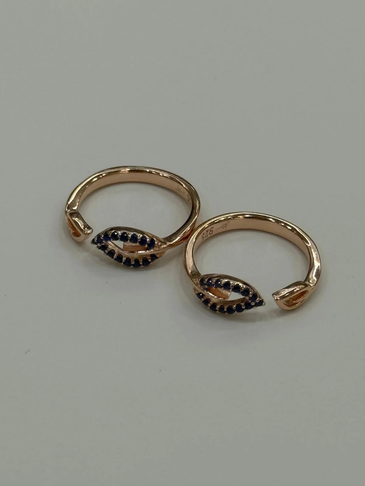 Rose gold toe rings with black gemstones on a light gray background