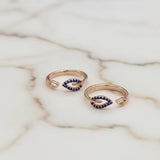 Two gold toe rings with blue gemstones on a marble surface