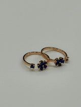 Rose gold toe ring with blue gemstones on a light gray background