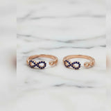 Two rose gold toe  rings with blue gemstones on a marble background