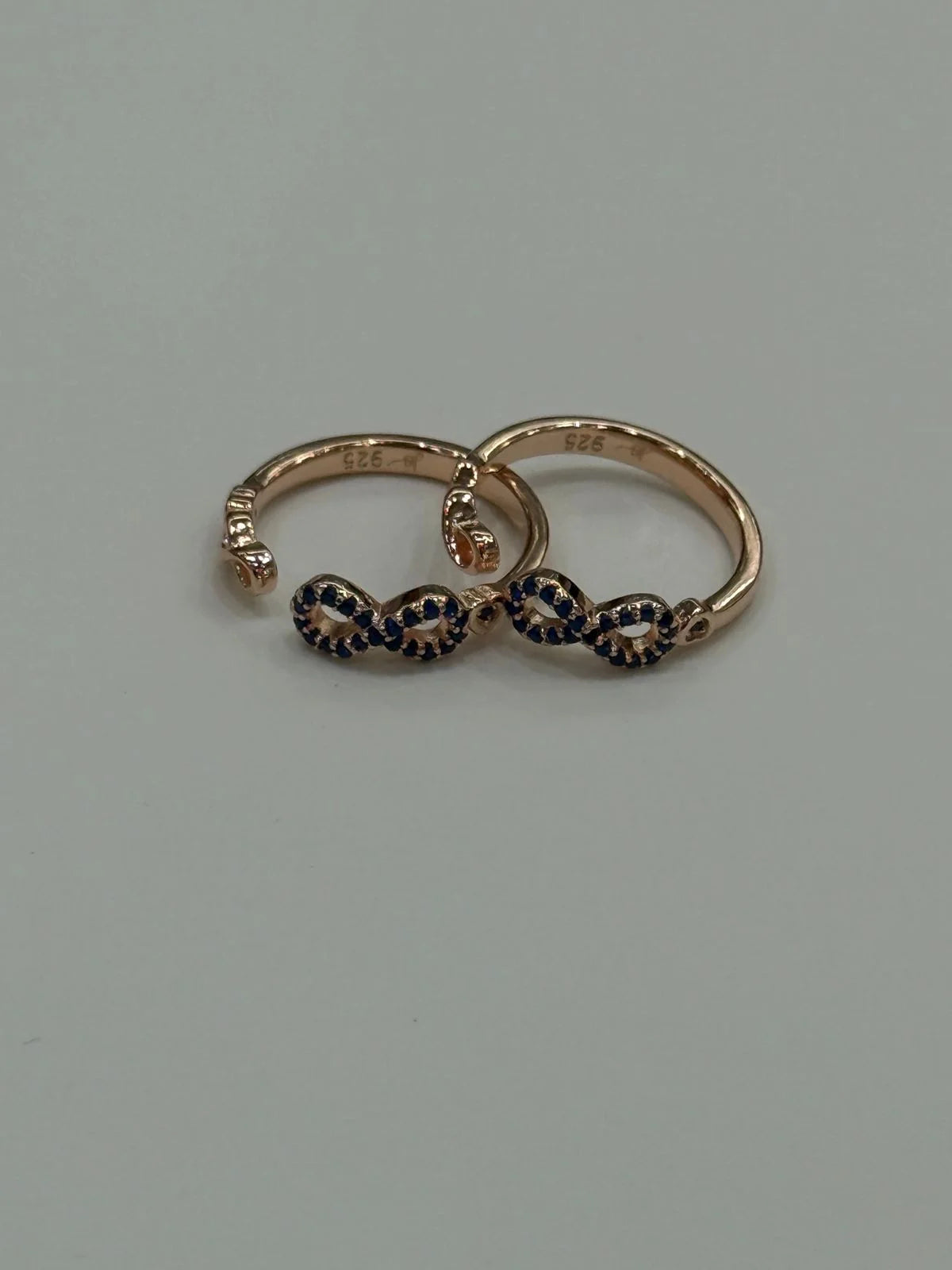 Pair of gold toe rings with black gemstones on a gray background