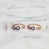 Rose gold infinity toe rings with blue gemstones on a marble background