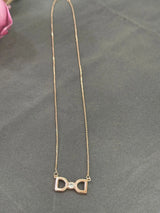 Gold bow-shaped necklace with a small diamond on a gray surface