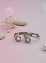 Silver toe ring with floral designs on a pink background