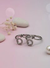 Silver toe ring with floral designs on a pink background