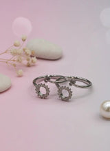 Silver toe ring with floral designs on a pink background