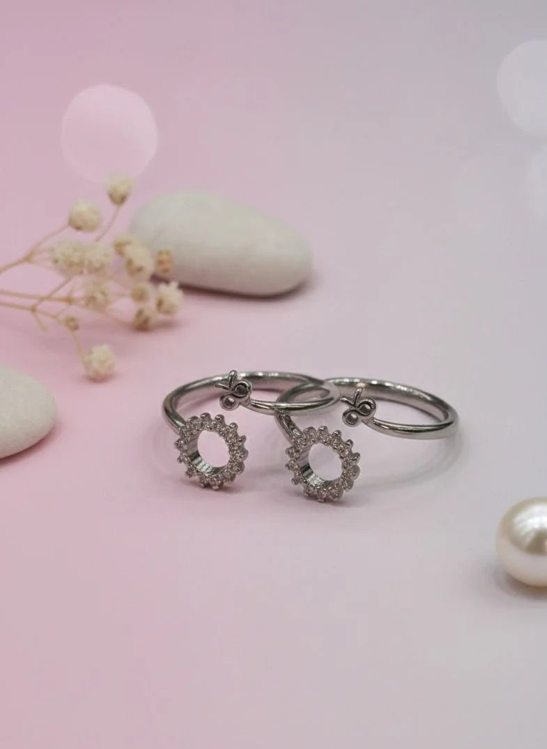 Silver toe ring with floral designs on a pink background