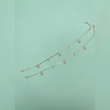 Gold anklet with small charms on a light green background