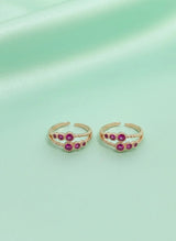 Pair of toe rings with red gemstones on a light green background