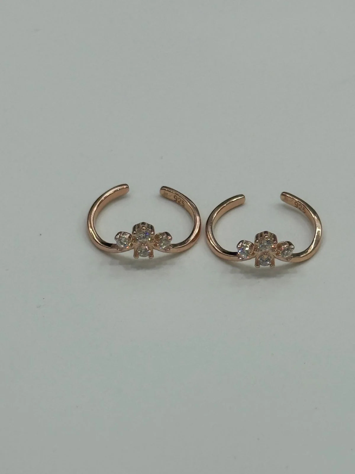 Rose gold ear rings with floral designs on a light gray background