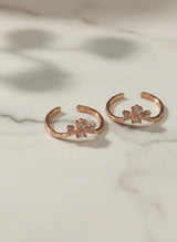 Rose gold toe rings with floral designs on a marble surface