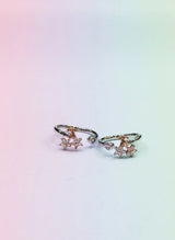 Pair of rose gold toe rings with small gemstones on a gradient background