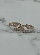 Two rose gold toe rings with diamond accents on a marble surface