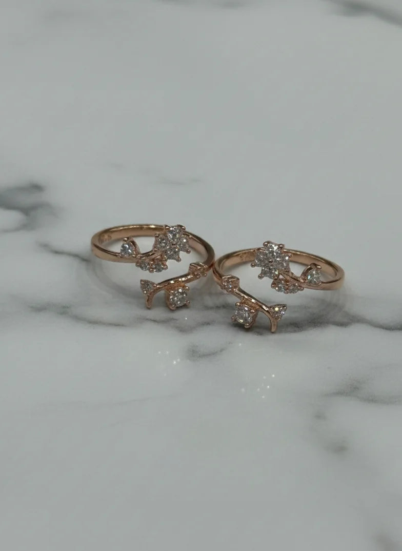Two rose gold toe rings with diamond accents on a marble surface