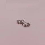 Pair of silver toe  rings with floral designs on a pink background