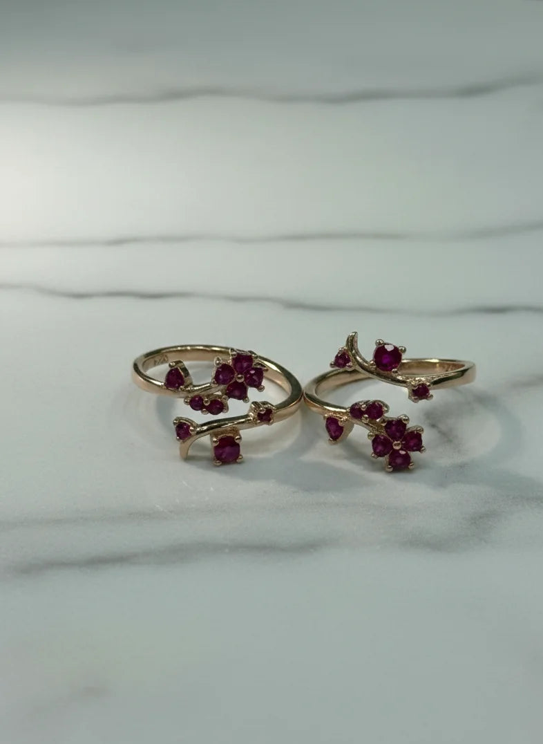 Two gold toe  rings with red gemstones on a marble surface