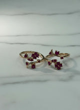Two gold toe  rings with red gemstones on a marble surface