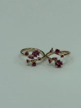 Two gold toe rings with red gemstones on a light gray background