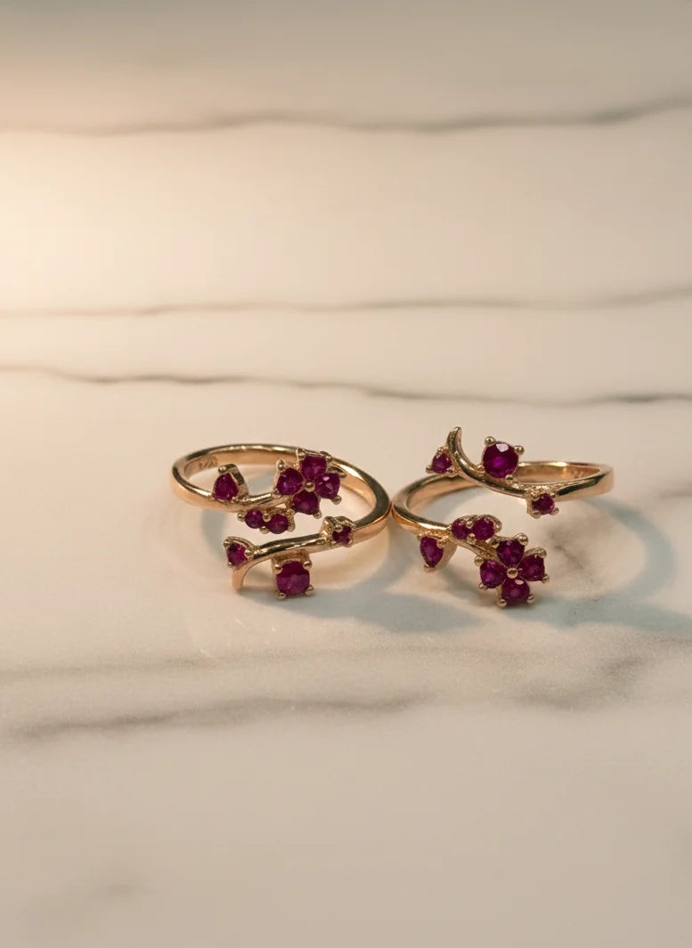 Gold toe rings with red gemstones on a marble surface