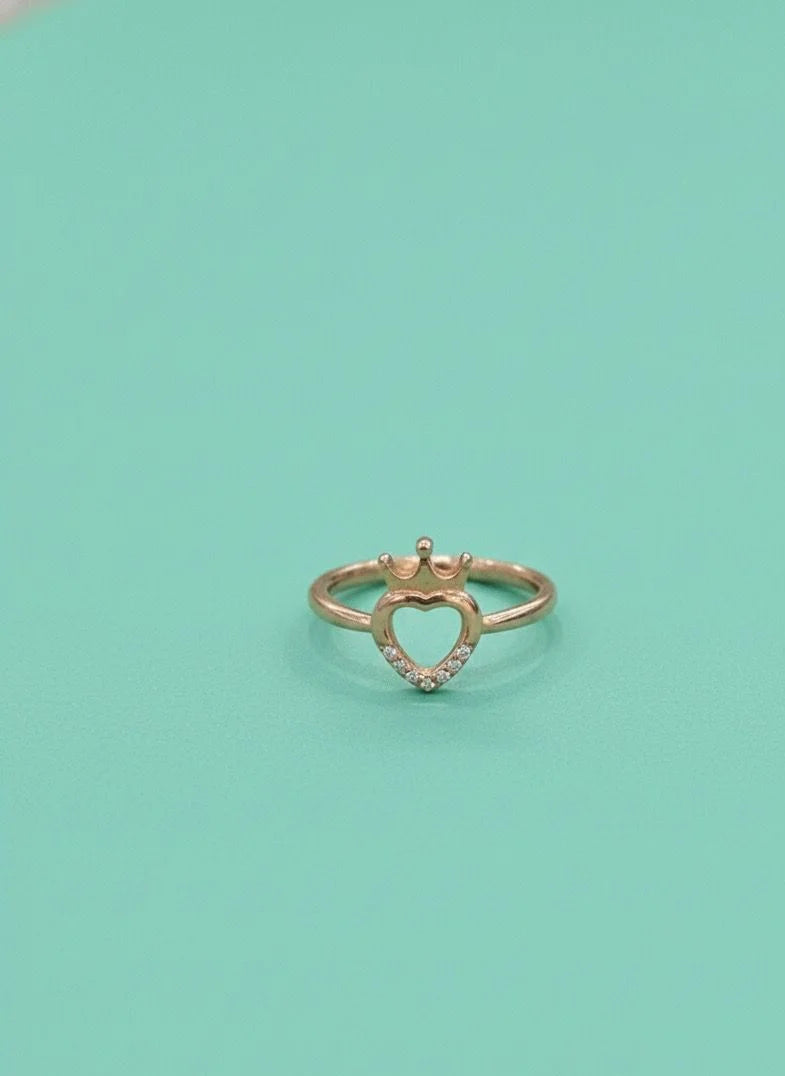 Heart-shaped gold ring with small diamonds on a light green background