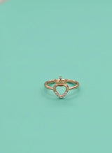 Heart-shaped gold ring with small diamonds on a light green background