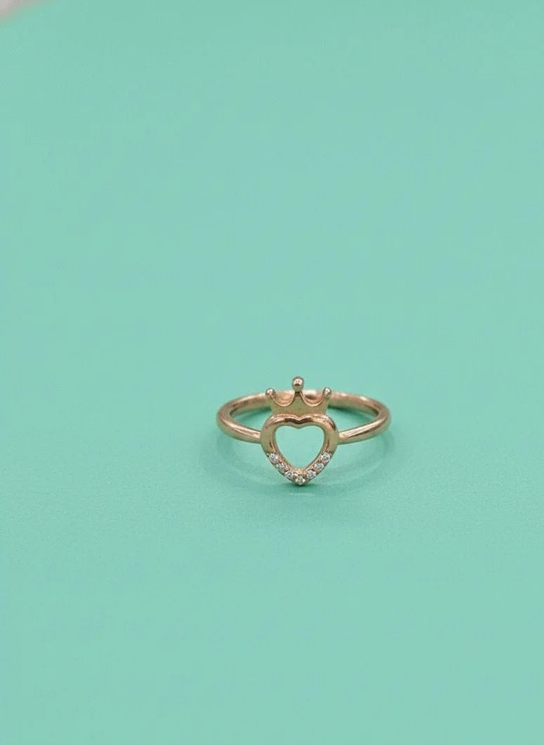 Heart-shaped gold ring with small diamonds on a light green background