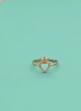 Heart-shaped gold ring with small diamonds on a light green background