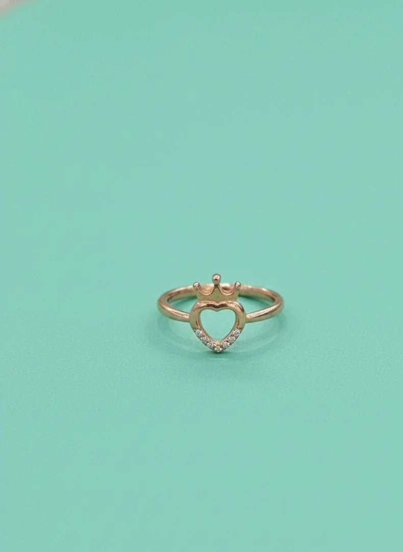 Heart-shaped gold ring with small diamonds on a light green background