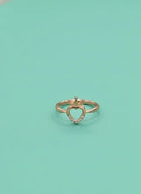Heart-shaped gold ring with small diamonds on a light green background