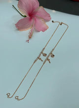 Rose gold anklet on a light blue surface with a pink flower