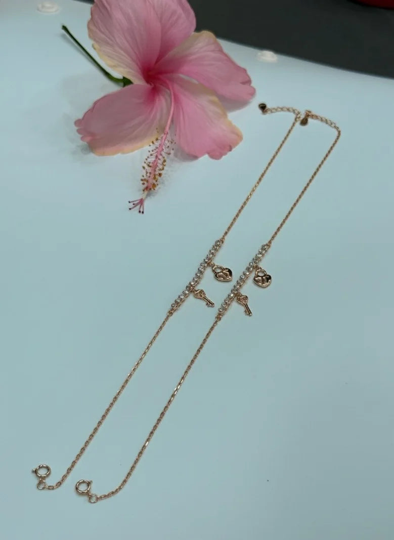 Rose gold anklet on a light blue surface with a pink flower
