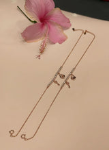 Rose gold anklet with floral design on a beige surface with pink flower