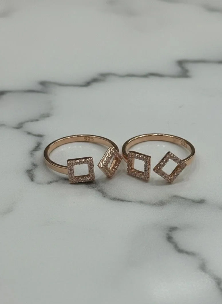 Two rose gold toe  rings with square designs on a marble surface