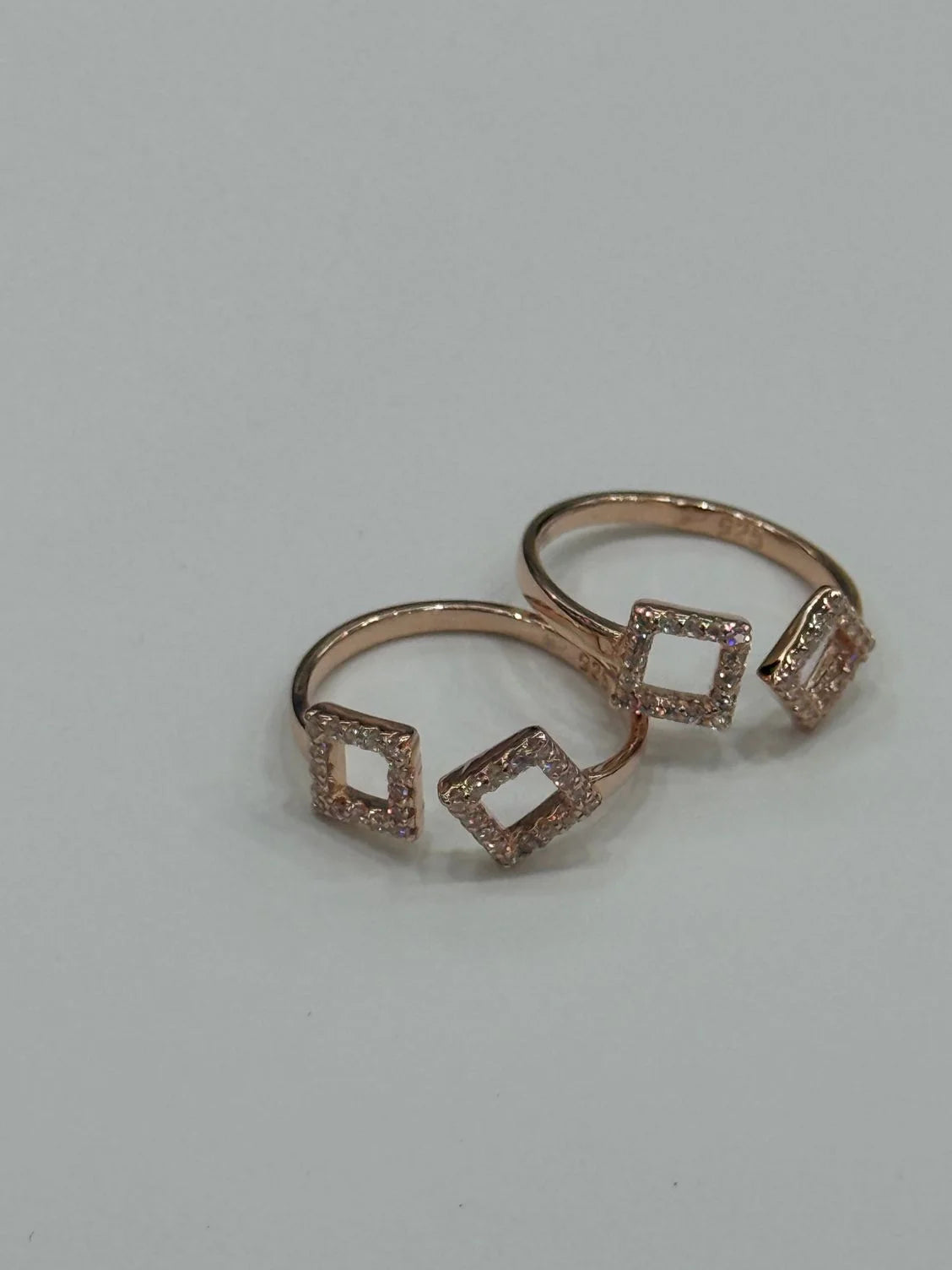 Rose gold toe ring with diamond-shaped designs on a light gray background