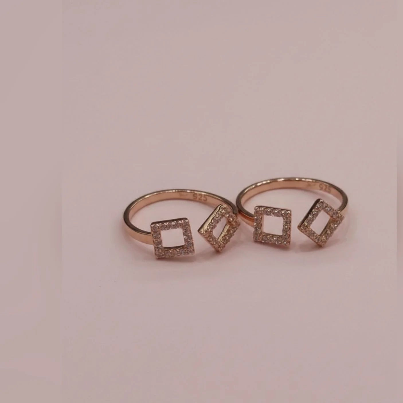 Rose gold toe  ring with square-shaped gemstones on a pink background
