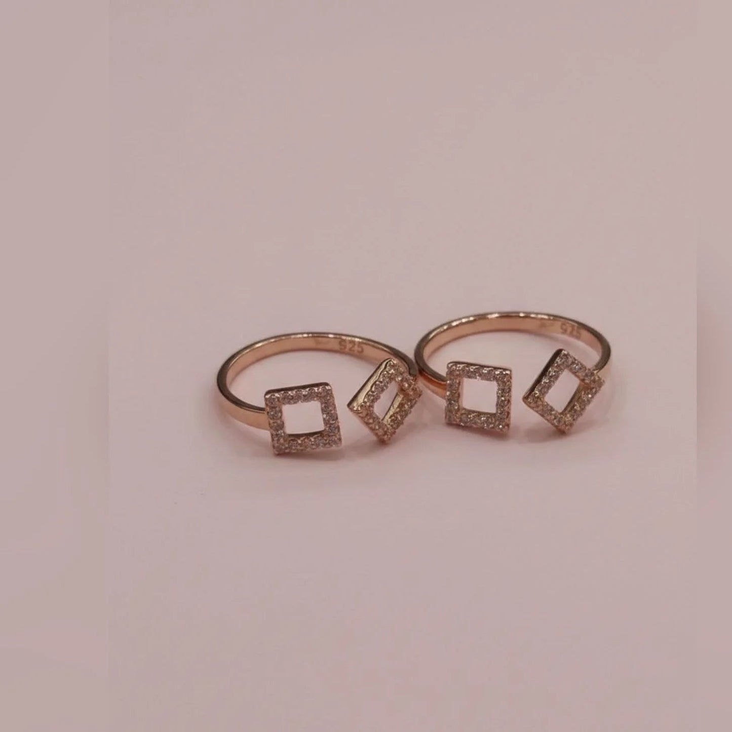 Rose gold toe ring with square-shaped gemstones on a pink background
