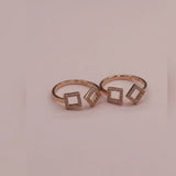 Rose gold toe ring with square-shaped gemstones on a pink background