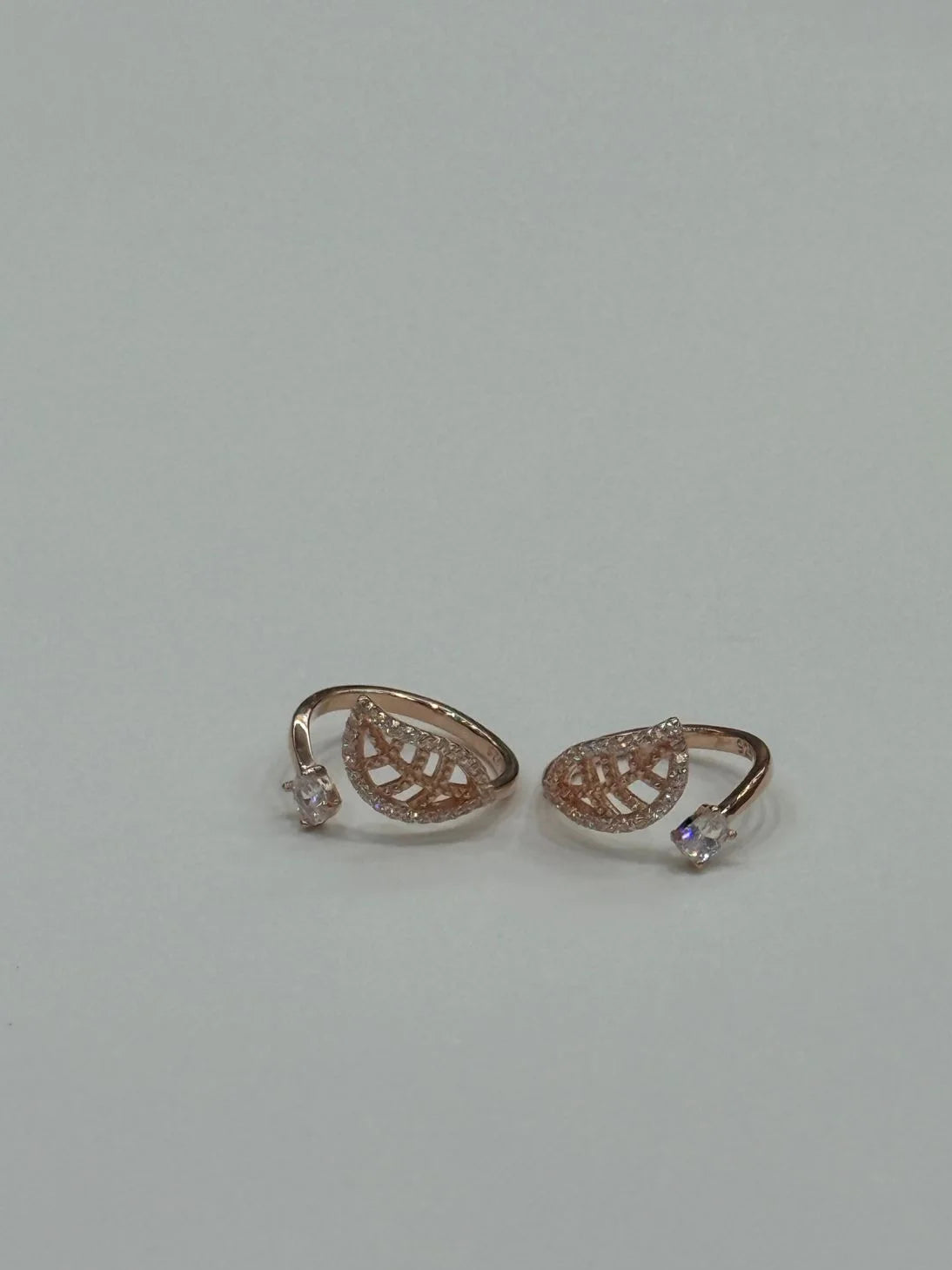Pair of rose gold toe rings with gemstones on a light gray background