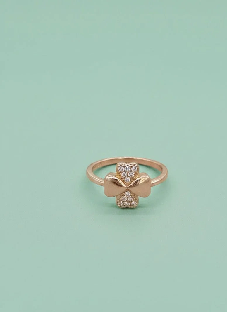 Rose gold ring with bow design on a light green background