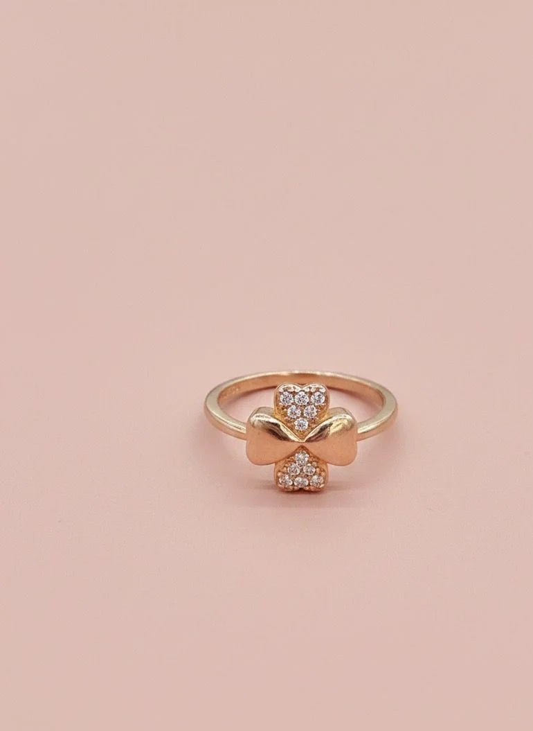 Gold ring with diamond accents on a pink background