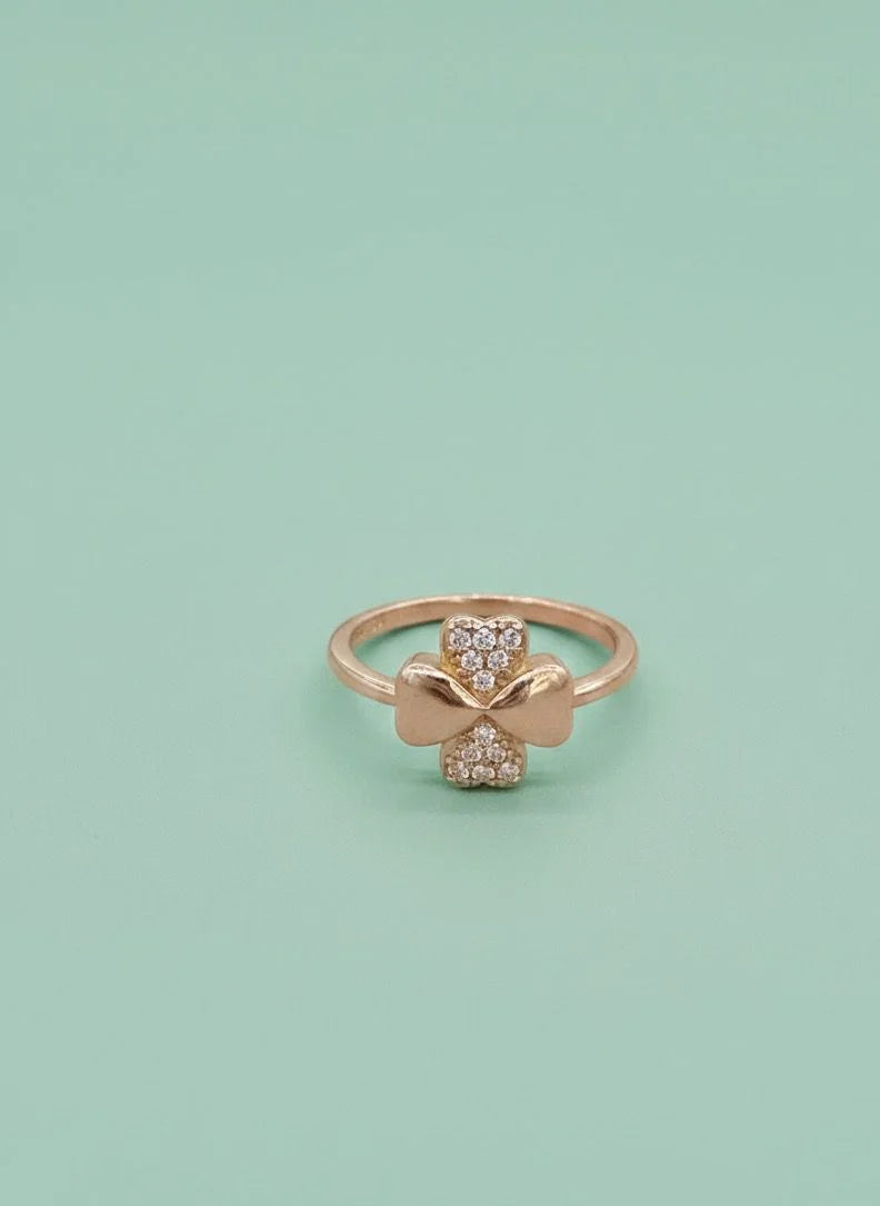 Rose gold ring with bow design on a light green background